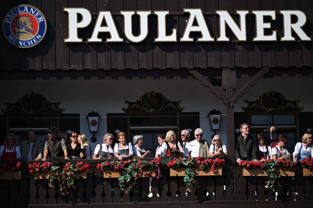 أشخاص يرتدون الأزياء البافارية التقليدية يقفون على شرفة خيمة البيرة في أرض المعارض خلال عرض الأزياء في يوم افتتاح مهرجان أكتوبر.