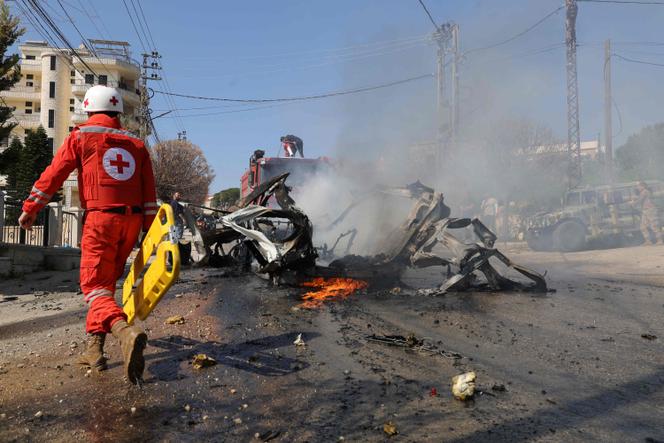 يتجه أحد إنقاذ الصليب الأحمر نحو سيارة مشتعلة بعد أن تأثرت به ضربة إسرائيلية في قرية بورج مولوك ، في جنوب لبنان في 15 مارس 2025.