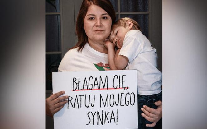 في صورة تم التقاطها من موقع Siepomaga عبر الإنترنت ، تحمل Monika طفلها بين ذراعيها ، وإغنياس ، وعلامة حيث يمكننا قراءة 