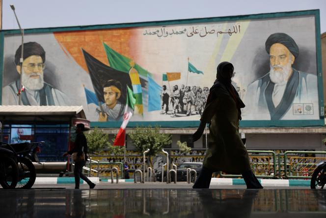 أمام لوحة جدارية تمثل المرشد الإيراني الأعلى ، آية الله علي خامني (على اليسار) ، وسلفه روه الله خميني ، في طهران ، في 24 يونيو 2025.