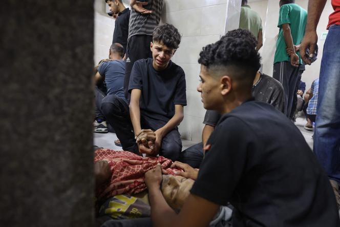أمام جثة أحد الوالدين الذين قتلوا بنيران إسرائيلية عند نقطة توزيع المساعدات الغذائية التي أنشأتها مؤسسة غزة الإنسانية (GHF) ، في مستشفى الودة ، في معسكر اللاجئين في نوسارات ، في وسط قطاع غزة ، في 24 يونيو 2025.
