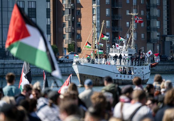 يشاهد المتظاهرون الذين يلوحون بالأعلام الفلسطينية قارب 