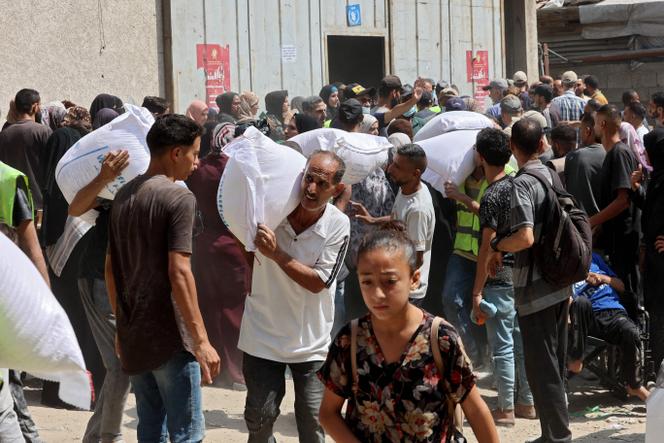 يحمل الفلسطينيون أكياس الدقيق في مستودع في برنامج الأطعمة العالمية للأمم المتحدة في شارع الجلة في مدينة غزة ، في وسط قطاع غزة ، في 12 يوليو 2025.