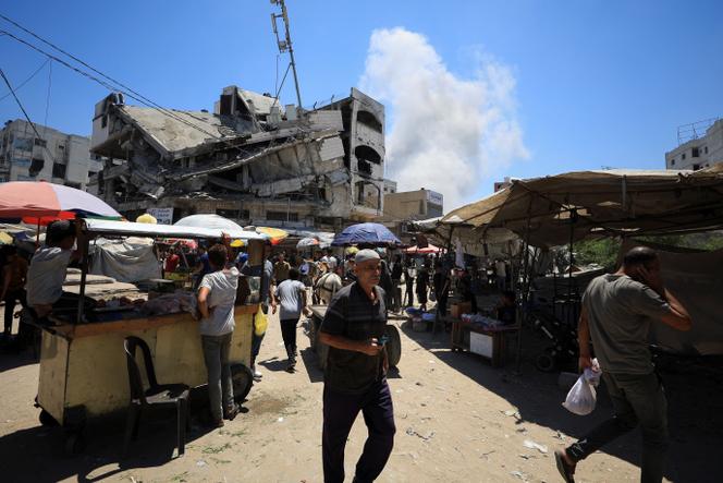 يمشي الفلسطينيون بعد ضربات الإسرائيلية في المباني في سوق بلدة غزة القديمة في مدينة غزة ، 9 يوليو 2025.