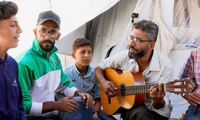 أحمد أبو أمشا ، على الجيتار ، منشئ مجموعة غزة بيردز الغنائية ، في معسكره ، في غزة ، 30 مايو 2025.