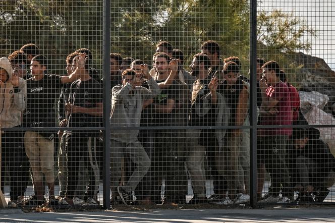 يتم جمع المهاجرين من قبل حراس الساحل اليوناني ، خلف سياج ، بعد أن هبطوا شحنة في ميناء لافريو ، في أثينا ، في 10 يوليو 2025.