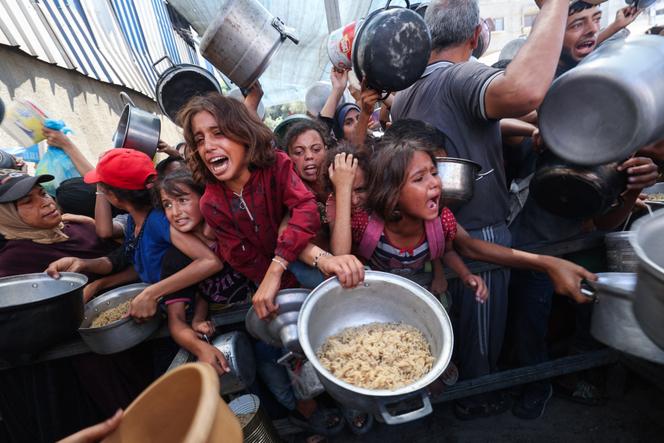 يتجول الفلسطينيون لتلقي وجبة ساخنة وزعتها جمعية خيرية في معسكر Nuserat للاجئين ، في قطاع غزة الذي حاصرته إسرائيل في 4 سبتمبر 2025.