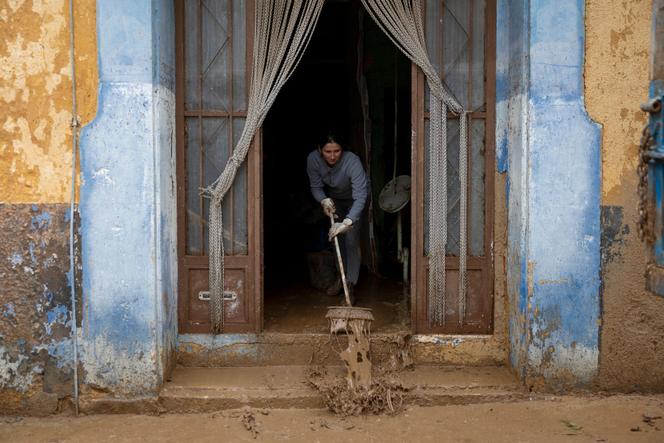 إحدى السكان تقوم بإزالة الطين من عملها في جودال في 1 أكتوبر 2025، بعد هطول أمطار غزيرة على جنوب كاتالونيا في اليوم السابق. (تصوير جوسيب لاغو/ وكالة الصحافة الفرنسية)