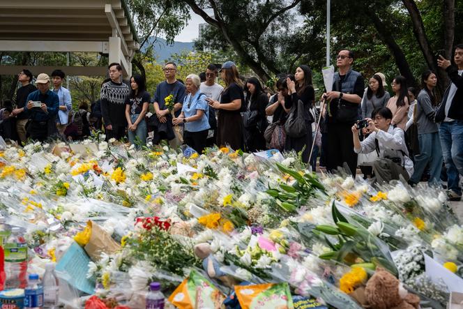 يصلي الناس، الأحد 30 نوفمبر 2025، في هونغ كونغ، أمام الزهور الموضوعة تكريمًا لضحايا الحريق الذي دمر مجمعًا سكنيًا في هونغ كونغ قبل أربعة أيام.