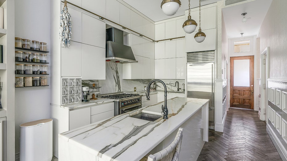 يحتوي المطبخ على جزيرة مركزية كبيرة مع مغسلة ثانية، بالإضافة إلى رف توابل على الحائط.