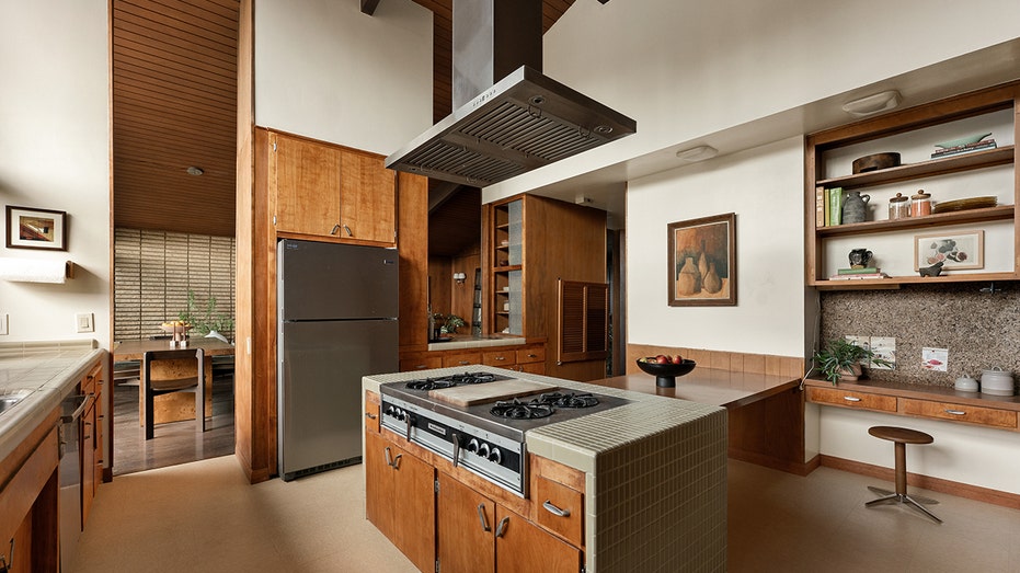 يتميز المطبخ بجزيرة مركزية لتناول الطعام وأرفف مدمجة وإطلالات على الفناء الخلفي.