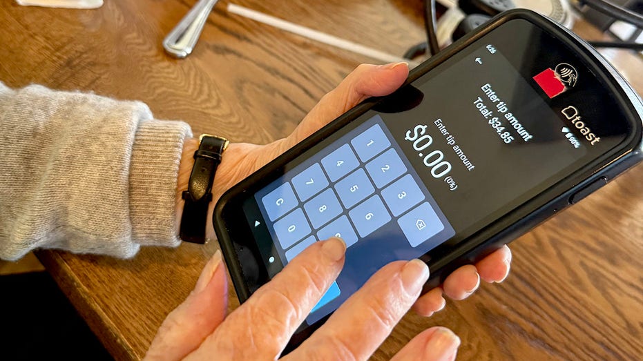 امرأة تدخل مبلغ الإكرامية في مطعم باستخدام جهاز لوحي محمول في فلوريدا.