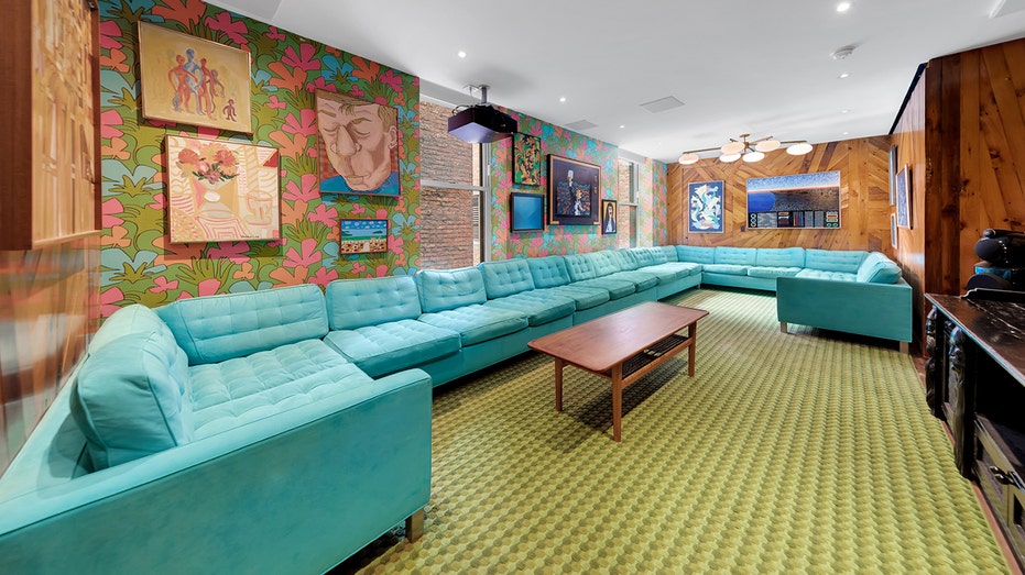 يتميز المنزل بديكور على طراز السبعينيات، بما في ذلك ورق حائط مزين بالزهور وأريكة زرقاء كبيرة.