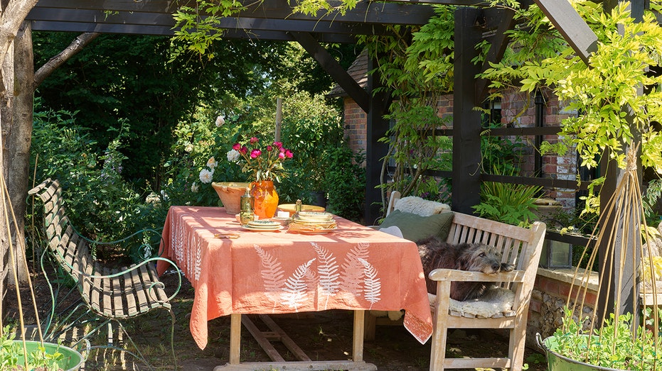 تقع منطقة تناول الطعام في الهواء الطلق تحت شرفة خشبية.