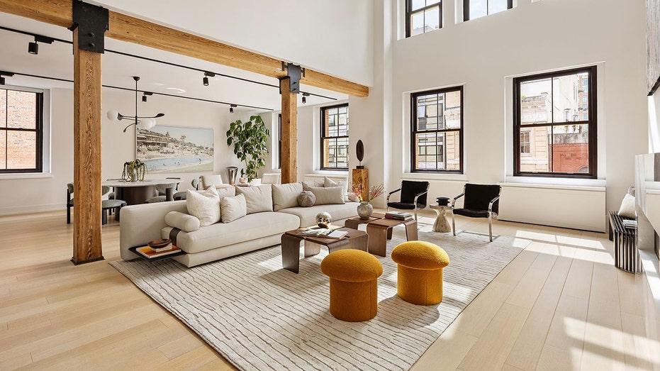 غرفة معيشة ذات أسقف عالية وعوارض خشبية.