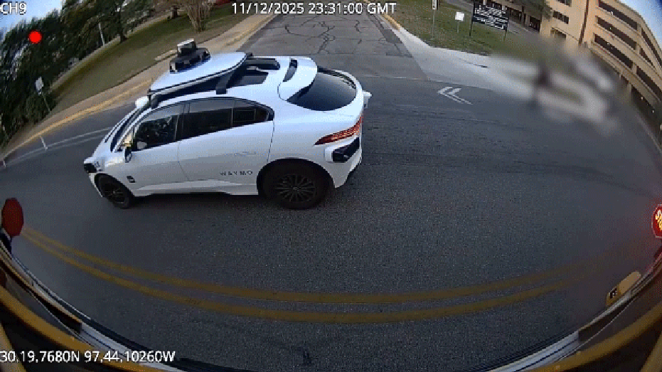 سيارة Waymo بيضاء تمر بعلامات توقف الحافلات المدرسية