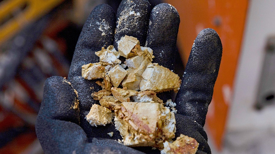 عامل يحمل عينة من التربة في منجم للأتربة النادرة