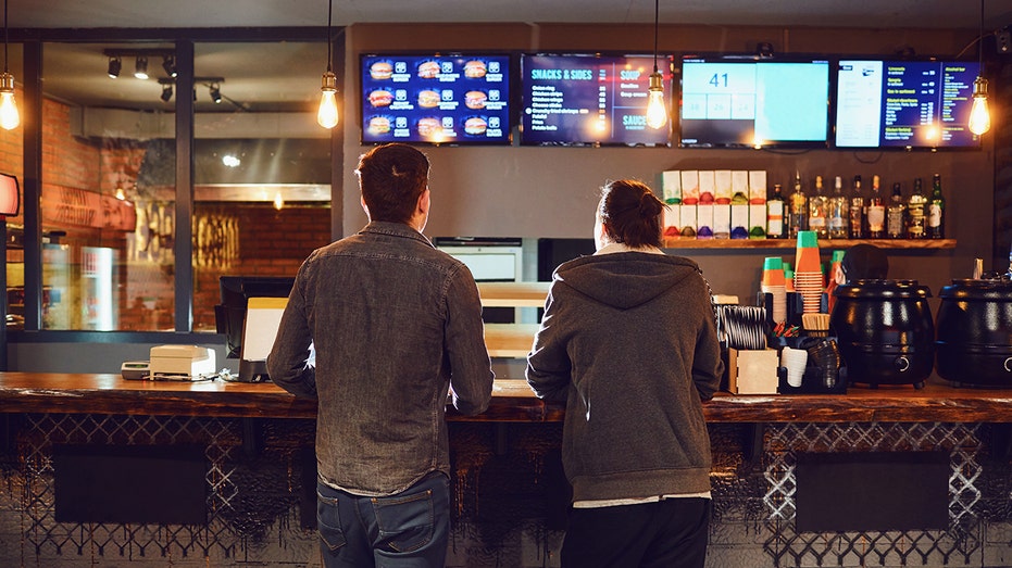 رجلان يختاران الطعام في مطعم للوجبات السريعة. مفهوم الوجبات الخفيفة في البار.