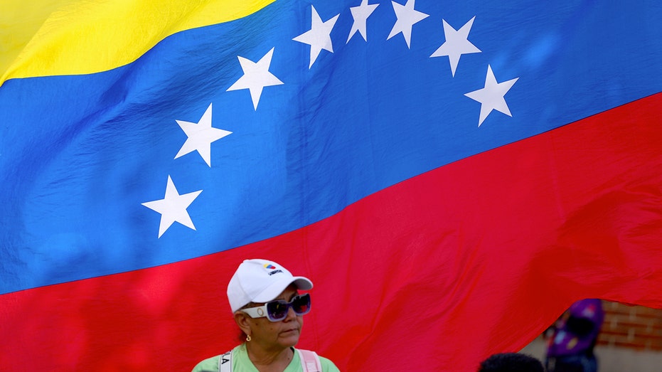 امرأة تقف أمام العلم الفنزويلي 