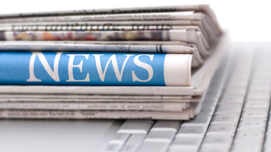 كومة من الصحف موضوعة أعلى لوحة مفاتيح الكمبيوتر