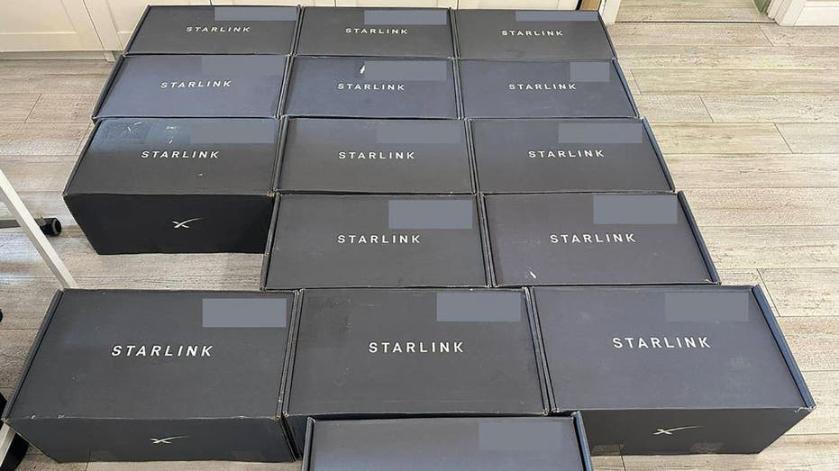 عدة صناديق Starlink سوداء موضوعة في صفوف على الأرض، مع وضع علامة على كل صندوق 