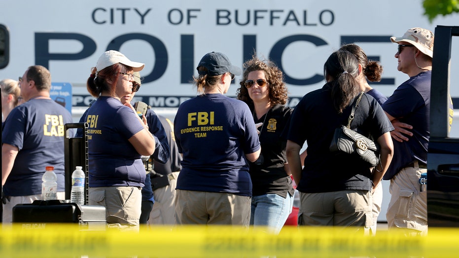 يتجمع ضباط إنفاذ القانون خارج أحد المتاجر الكبرى بينما يقوم المحققون بفحص مكان الحادث بعد إطلاق النار المميت.