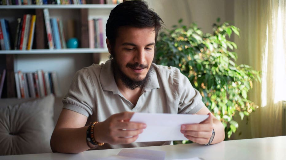 رجل يجلس في الداخل وينظر إلى قطعة من الورق.