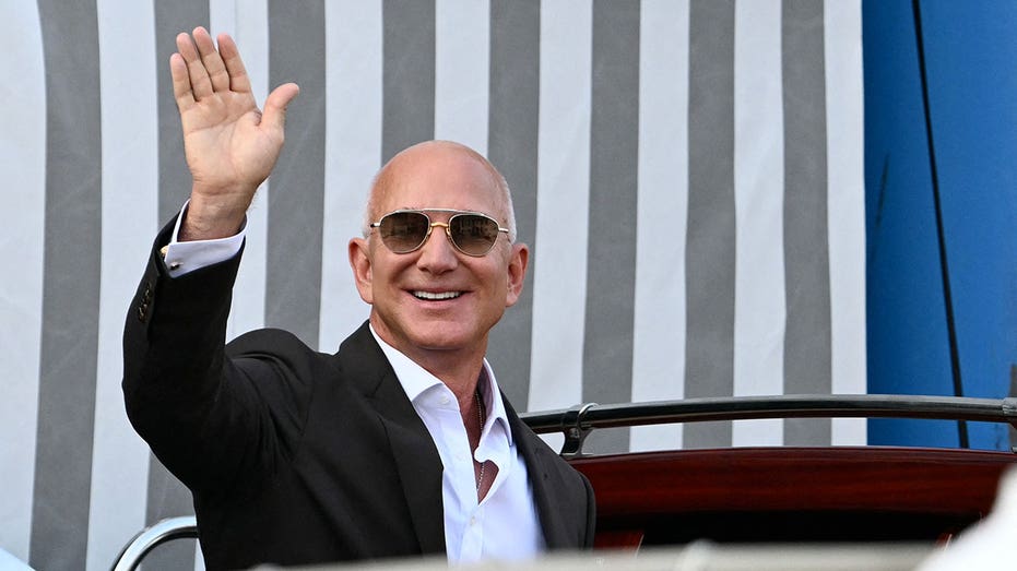 مؤسس أمازون جيف بيزوس يلوح بينما يستقل قارب سيارة أجرة في فندق أمان في البندقية في 26 يونيو 2026. يبحر المشاهير في اليخوت الفاخرة إلى البندقية هذا الأسبوع لحضور حفل زفاف يستمر ثلاثة أيام لقطب أمازون جيف بيزوس ولورين سانشيز، على الرغم من السكان المحليين الغاضبين الذين يقولون إن مدينة اليونسكو ليست ملعبًا للمليارديرات. وبحسب ما ورد، دعا قطب التكنولوجيا والصحفي حوالي 200 ضيف لحضور حفل زفافهم الذي تبلغ قيمته ملايين الدولارات في المدينة الإيطالية، والذي من المتوقع أن يبدأ في 26 يونيو وينتهي يوم السبت بحفل في مكان سري. (تصوير ستيفانو ريلانديني / وكالة الصحافة الفرنسية) (تصوير ستيفانو ريلانديني / وكالة الصحافة الفرنسية عبر غيتي إيماجز)