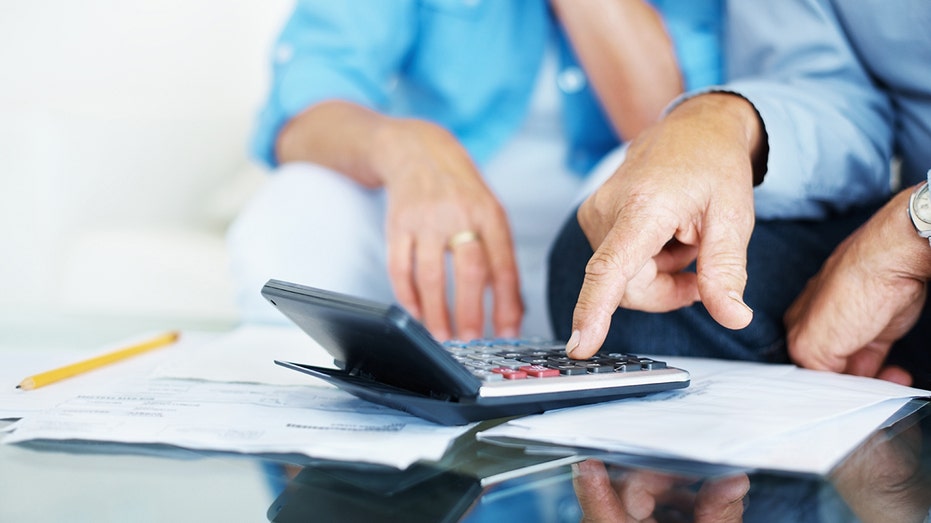 لقطة مقربة ليد رجل كبير السن يقوم بحساب الفواتير في المنزل