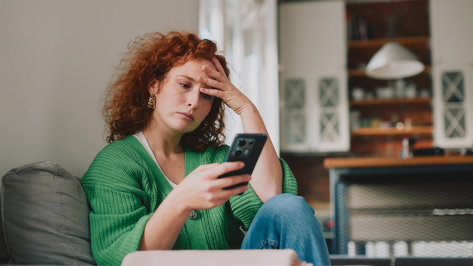 امرأة تنظر إلى الهاتف متوترة