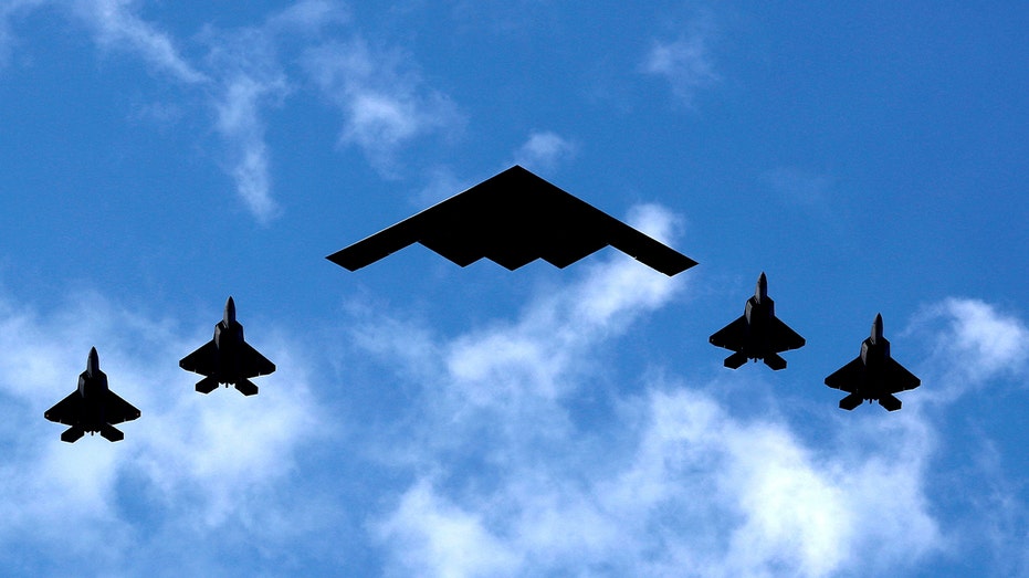 قاذفة قنابل من طراز B-2 محاطة بطائرات مقاتلة من طراز F-22 رابتور